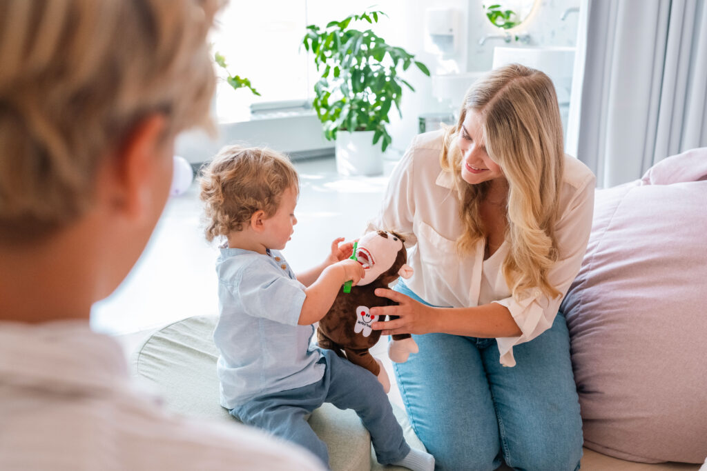 Mother teaching a child tooth brushing with a toy
