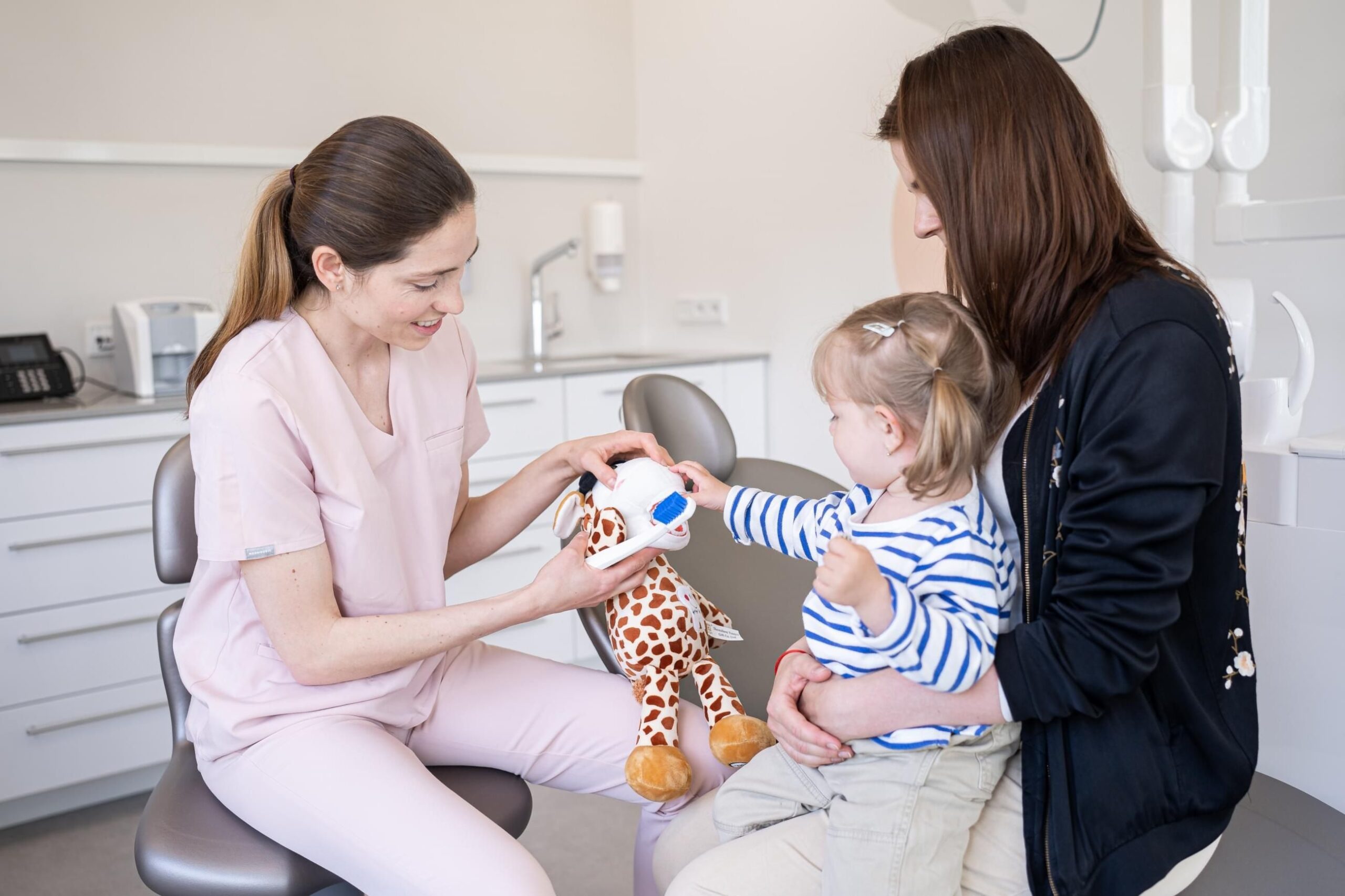 Zubní lékařka učí dítě čištění zubů pomocí hračky v ordinaci